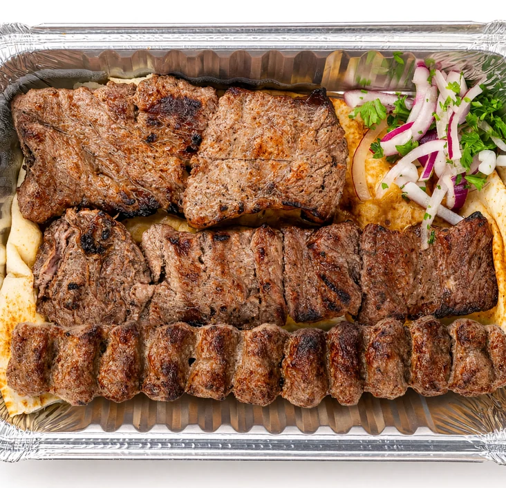 Shazdeh kabab: grilled steak pieces and a beef koobideh skewer on flatbread with sliced onion and herbs in a foil tray at AFRA Grill, Saskatoon