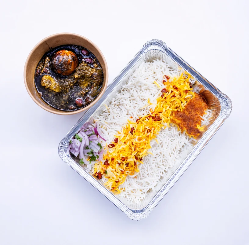 Ghormeh sabzi herb stew in a bowl beside a foil tray of white and saffron rice with tahdig at AFRA Grill, Saskatoon
