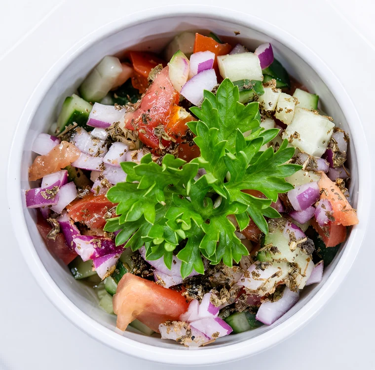 Shirazi salad of diced cucumber, tomato and red onion topped with fresh parsley in a white bowl at AFRA Grill, Saskatoon